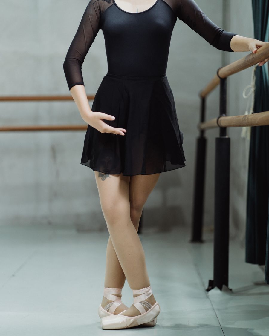 A dancer at the barre in a black wrap skirt
